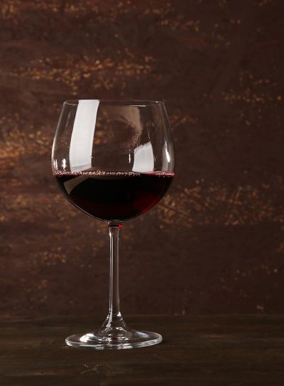 Goblet of red wine on wooden table on wooden wall background